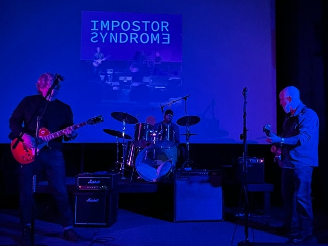 Impostor Syndrome performing live with blue stage lighting
